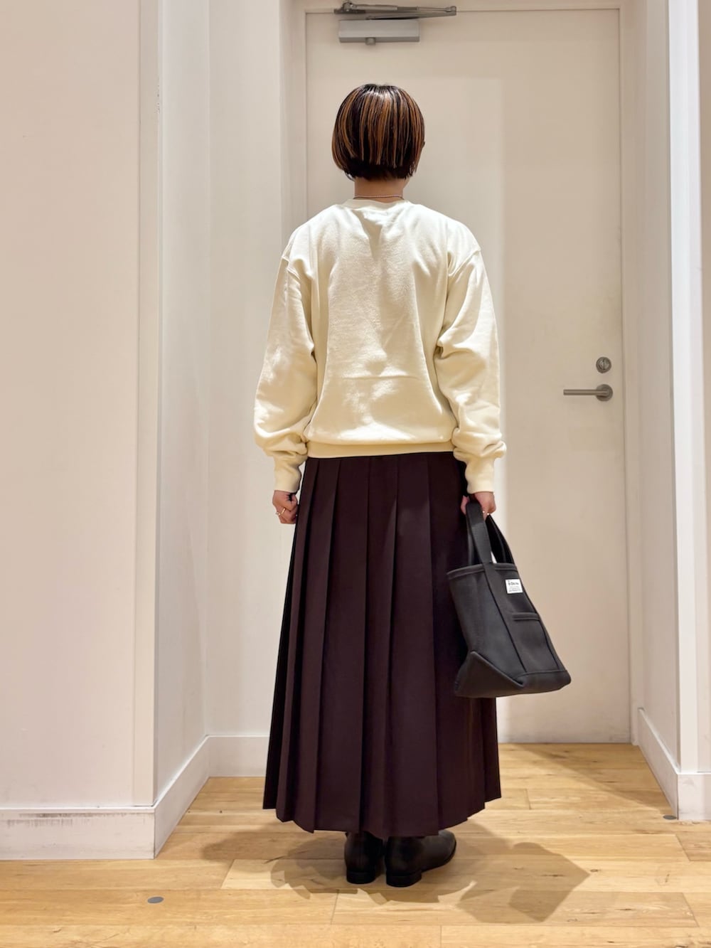 ホワイト系のスウェット、ブラウン系のスカート、グレー系のトートバッグを着用したレディースの秋コーディネートの5枚目の写真