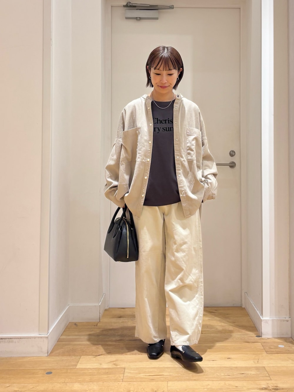 グレー系のTシャツ/カットソー、ホワイト系のその他パンツ、ブラック系のハンドバッグを着用したレディースの秋コーディネートの4枚目の写真