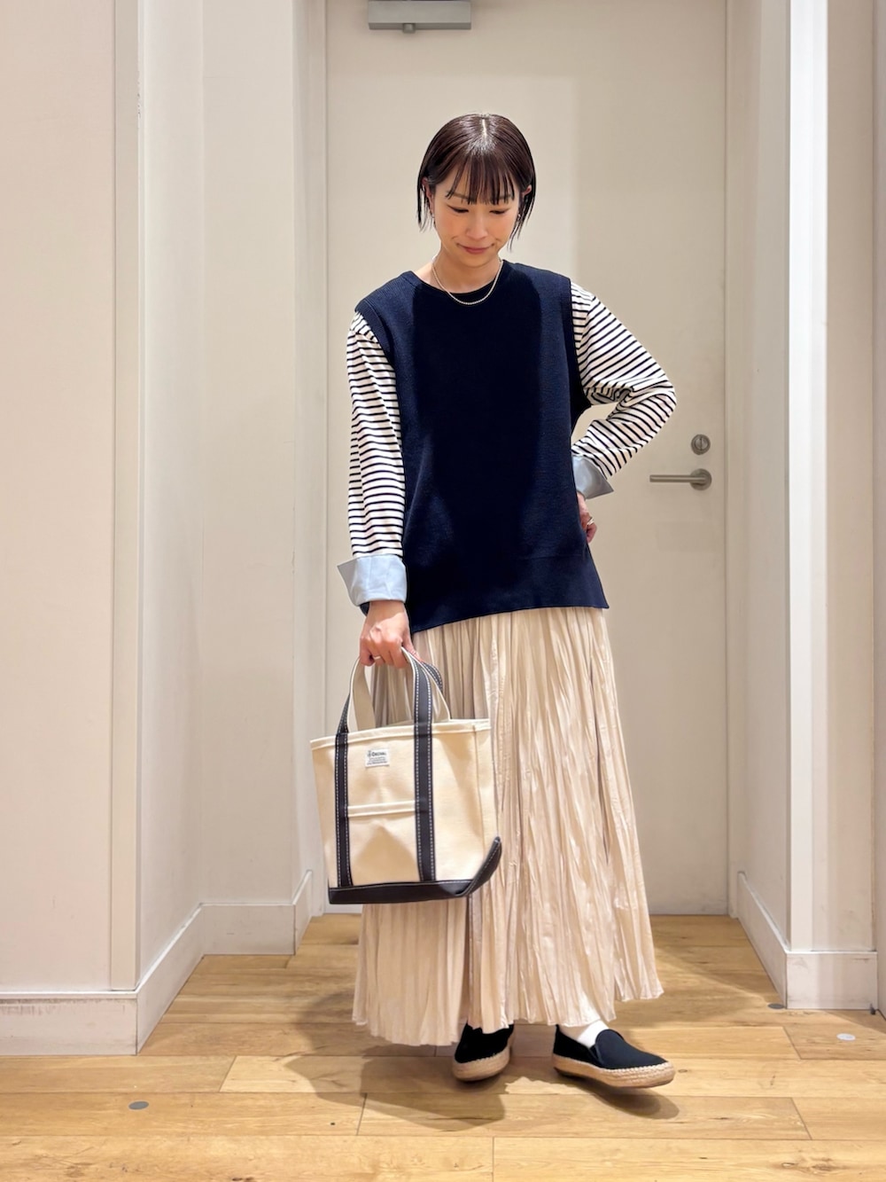 ホワイト系のTシャツ/カットソー、ベージュ系のステンカラーコート、ブルー系のベストを着用したレディースの春コーディネートの7枚目の写真