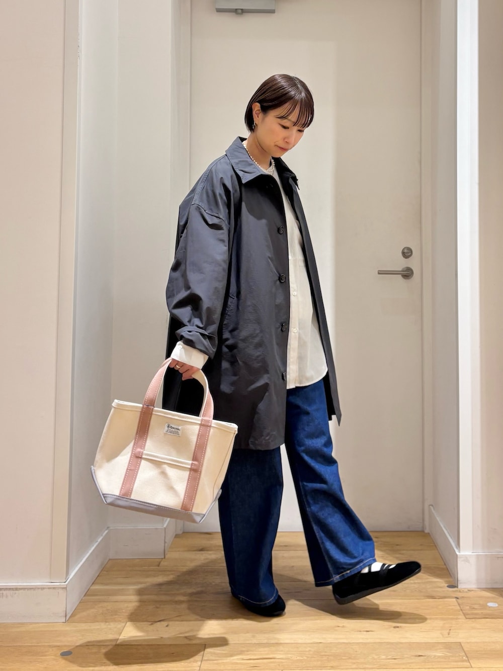 グレー系のステンカラーコート、グレー系のシャツ/ブラウス、ブルー系のデニムパンツを着用したレディースの春コーディネートの5枚目の写真