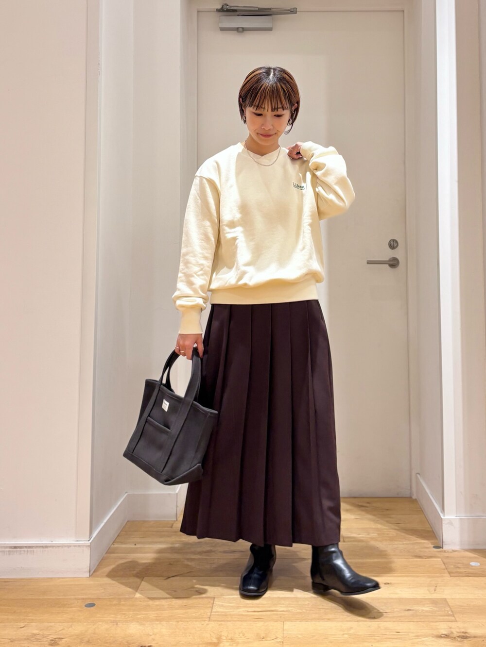 ホワイト系のスウェット、ブラウン系のスカート、グレー系のトートバッグを着用したレディースの秋コーディネートの3枚目の写真