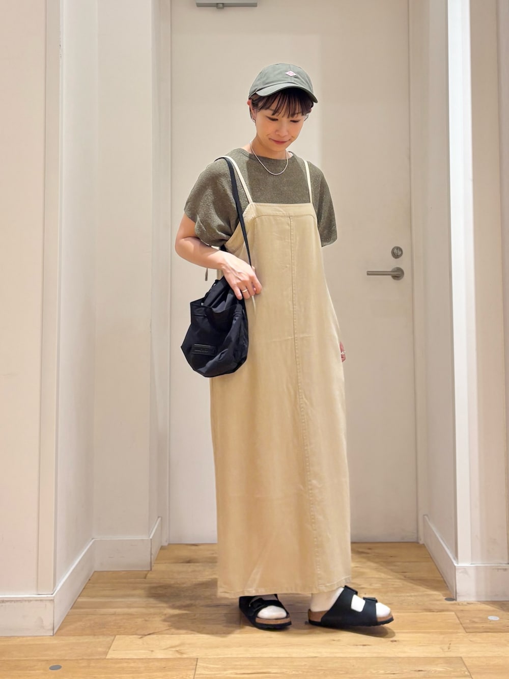 ベージュ系のワンピース、グリーン系のニット/セーター、ブラック系のサンダルを着用したレディースの夏コーディネートの4枚目の写真