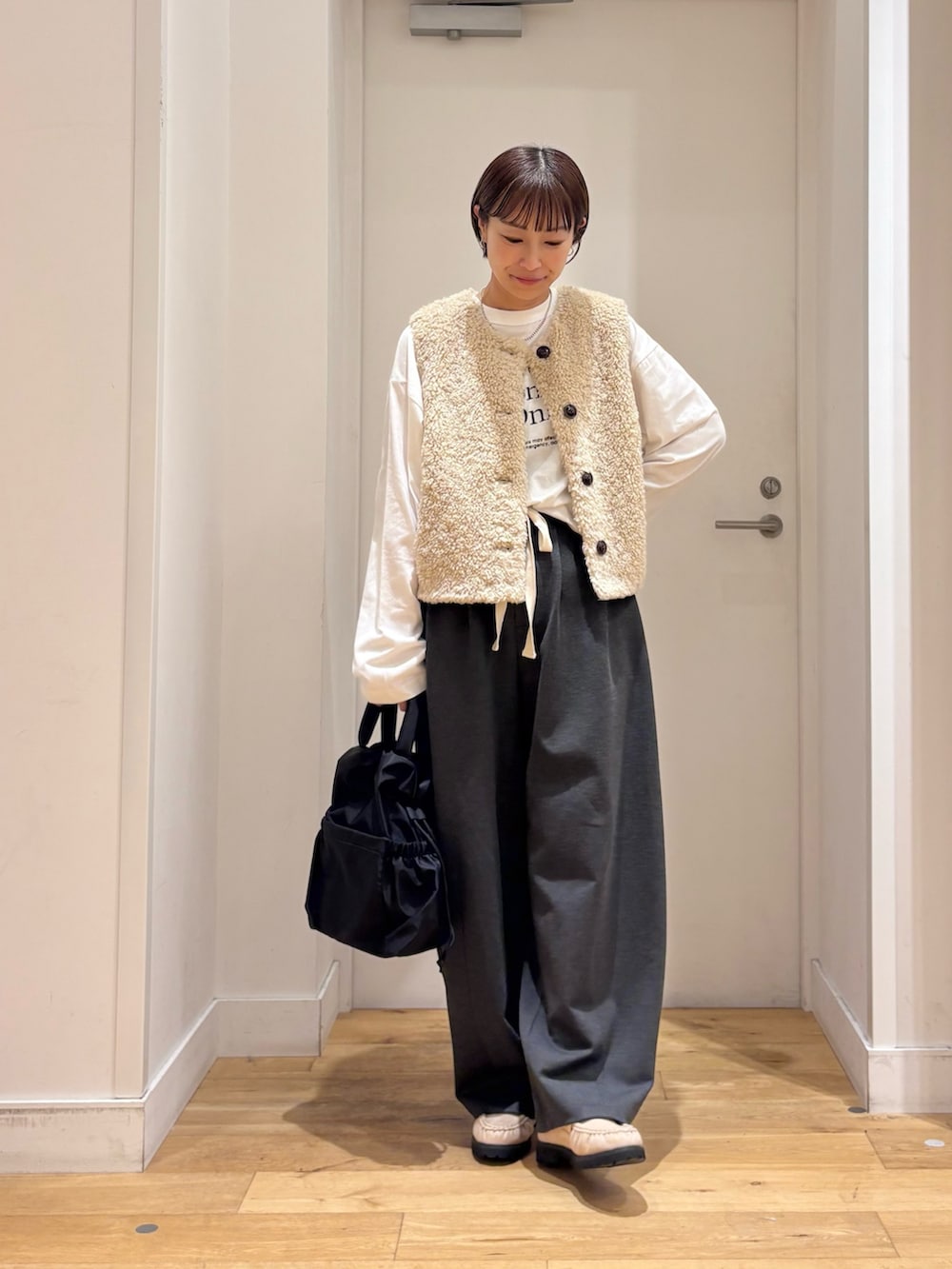 ベージュ系のダウンベスト、グレー系のその他パンツ、ホワイト系のTシャツ/カットソーを着用したレディースの秋コーディネートの4枚目の写真