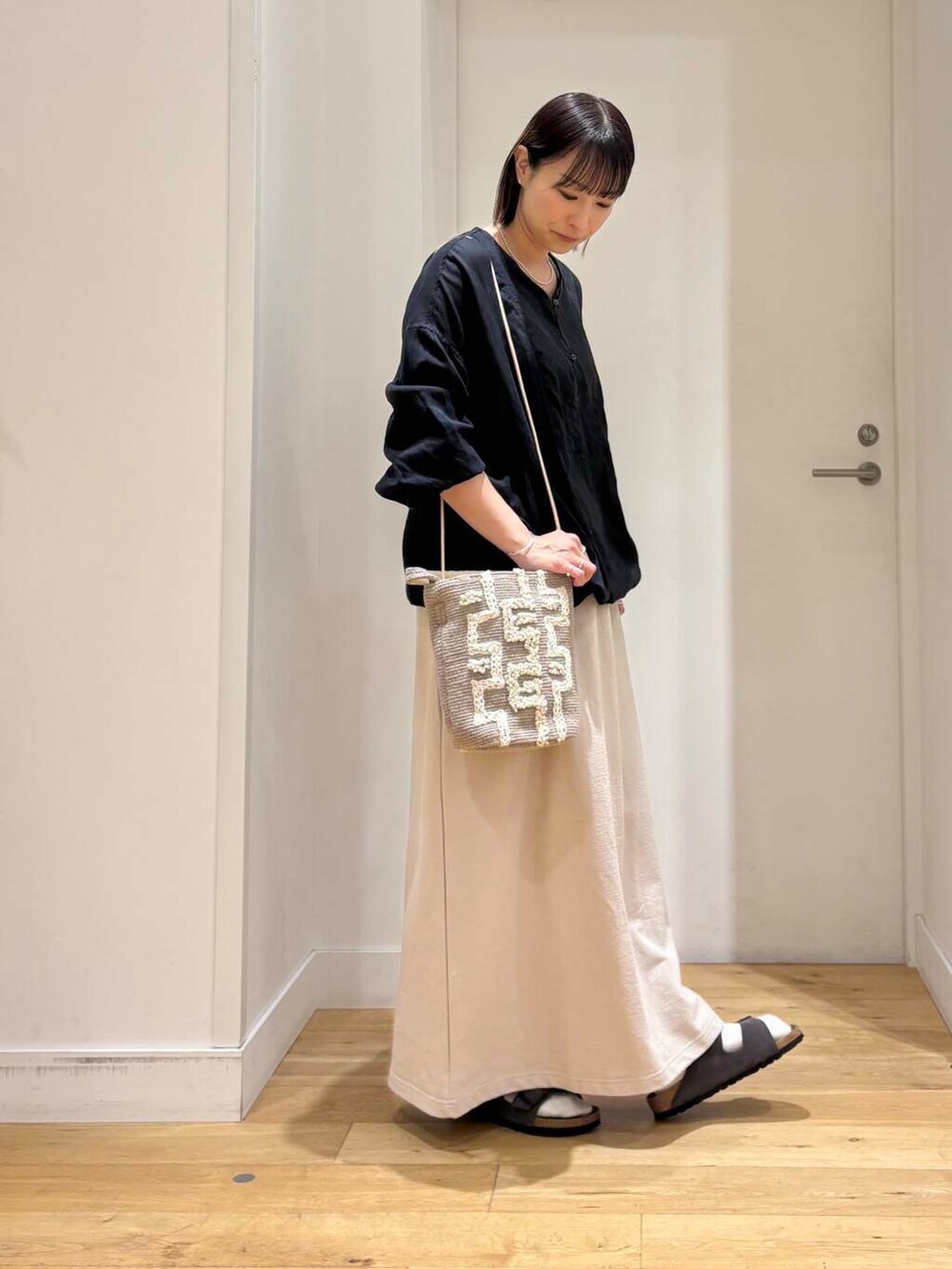 グレー系のショルダーバッグ、ブラック系のチュニック、グレー系のサンダルを着用したレディースの春コーディネートの4枚目の写真