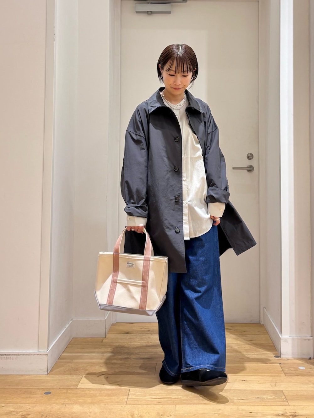 グレー系のステンカラーコート、グレー系のシャツ/ブラウス、ブルー系のデニムパンツを着用したレディースの春コーディネートの4枚目の写真