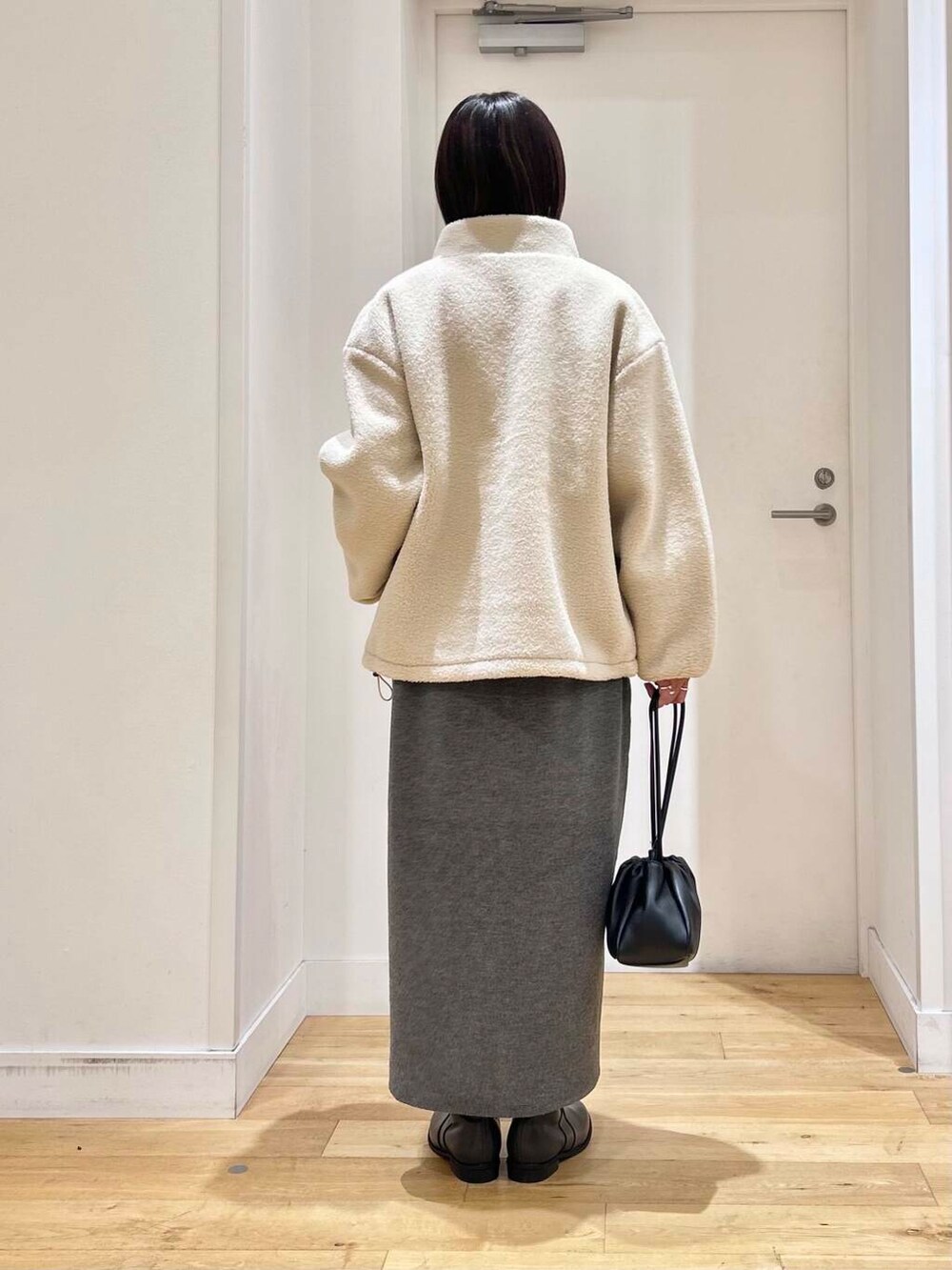 グレー系のブーツ、ホワイト系のブルゾン、グレー系のワンピースを着用したレディースの冬コーディネートの5枚目の写真