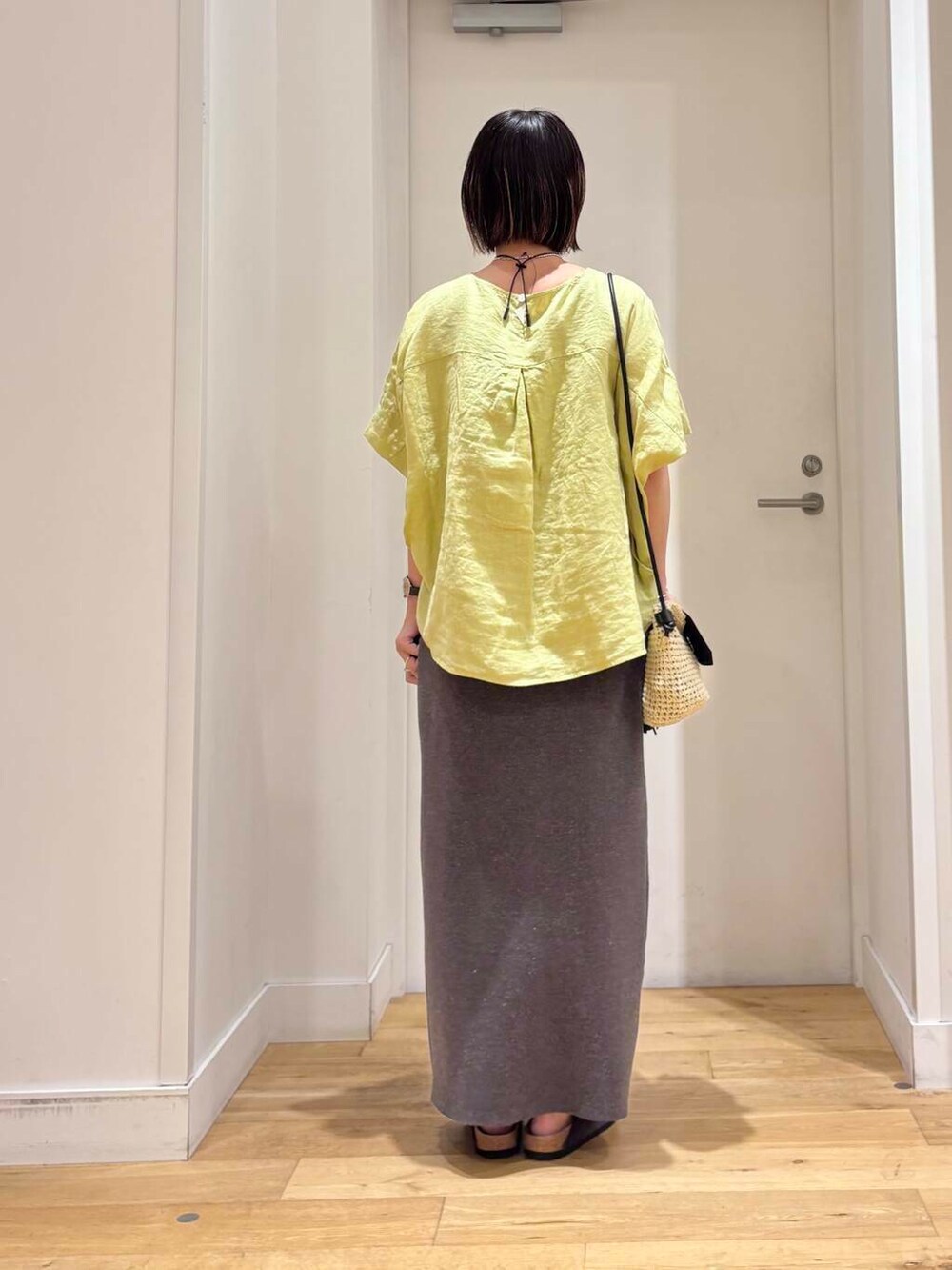 ベージュ系のショルダーバッグ、グレー系のスカート、グレー系のサンダルを着用したレディースの夏コーディネートの5枚目の写真