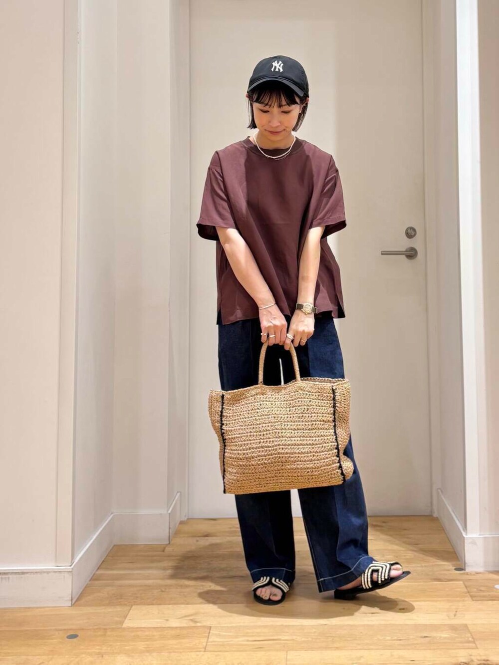 ベージュ系のトートバッグ、ブルー系のデニムパンツ、ブラック系のサンダルを着用したレディースの夏コーディネートの3枚目の写真