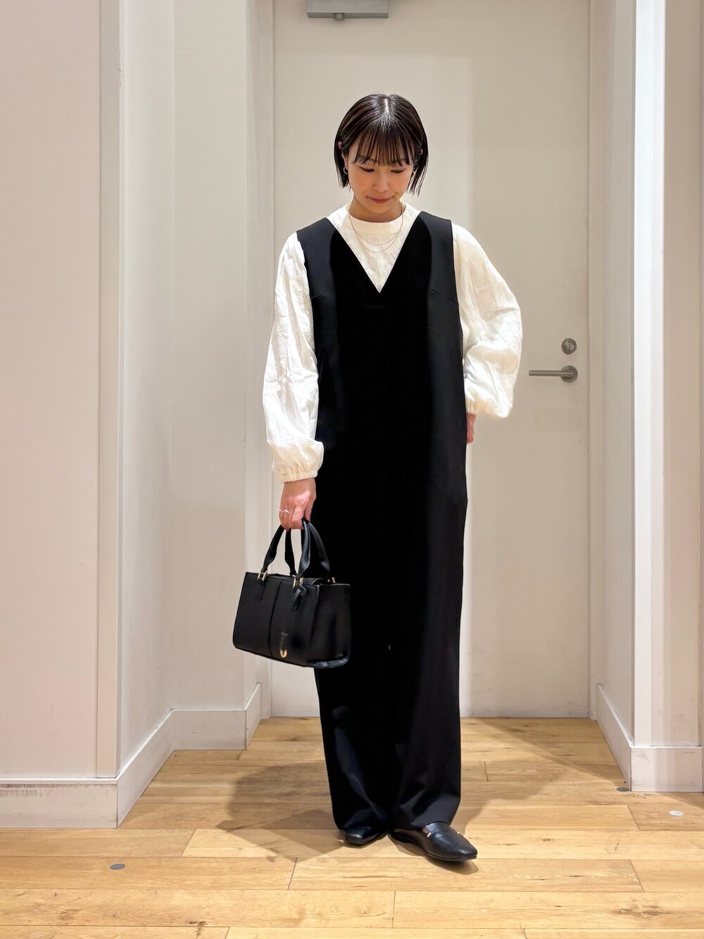 ブラック系のスーツジャケット、ホワイト系のシャツ/ブラウス、ブラック系のハンドバッグを着用したレディースの冬コーディネートの6枚目の写真