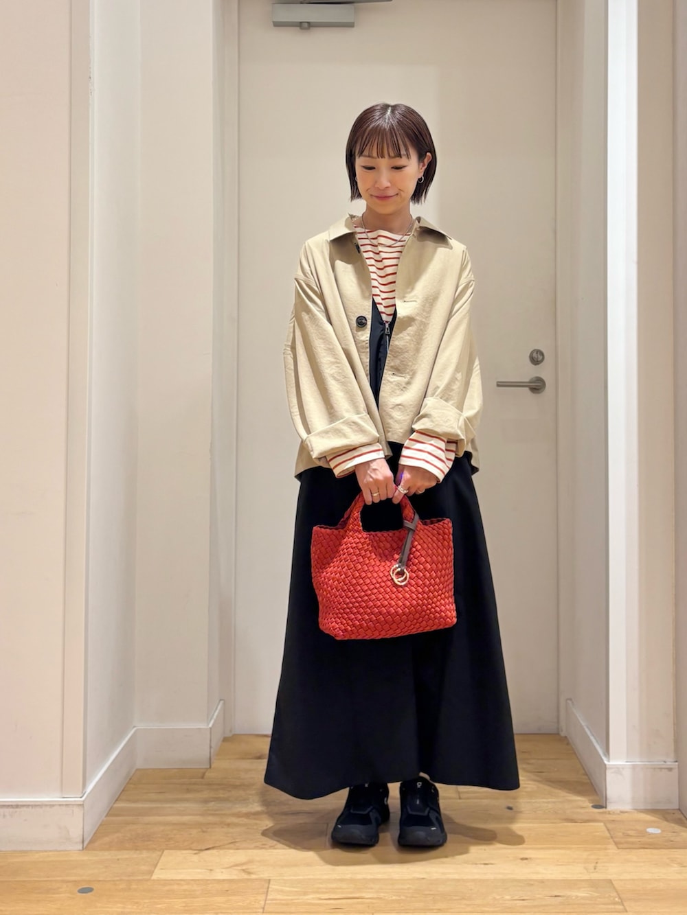 ブラック系のワンピース、ベージュ系のステンカラーコート、ホワイト系のTシャツ/カットソーを着用したレディースの秋コーディネートの3枚目の写真