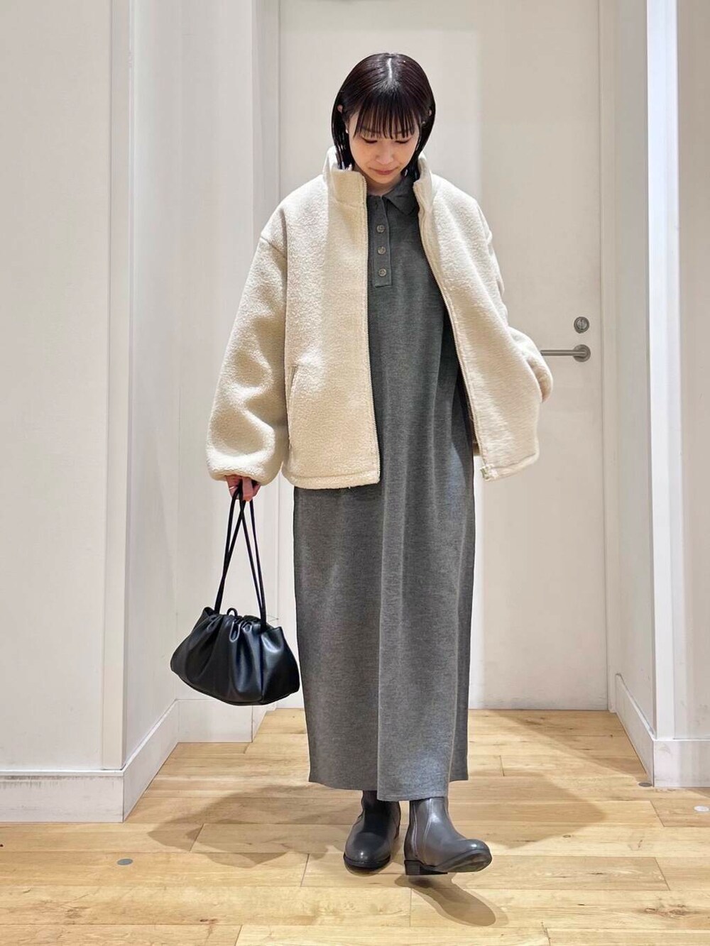 グレー系のブーツ、ホワイト系のブルゾン、グレー系のワンピースを着用したレディースの冬コーディネートの2枚目の写真