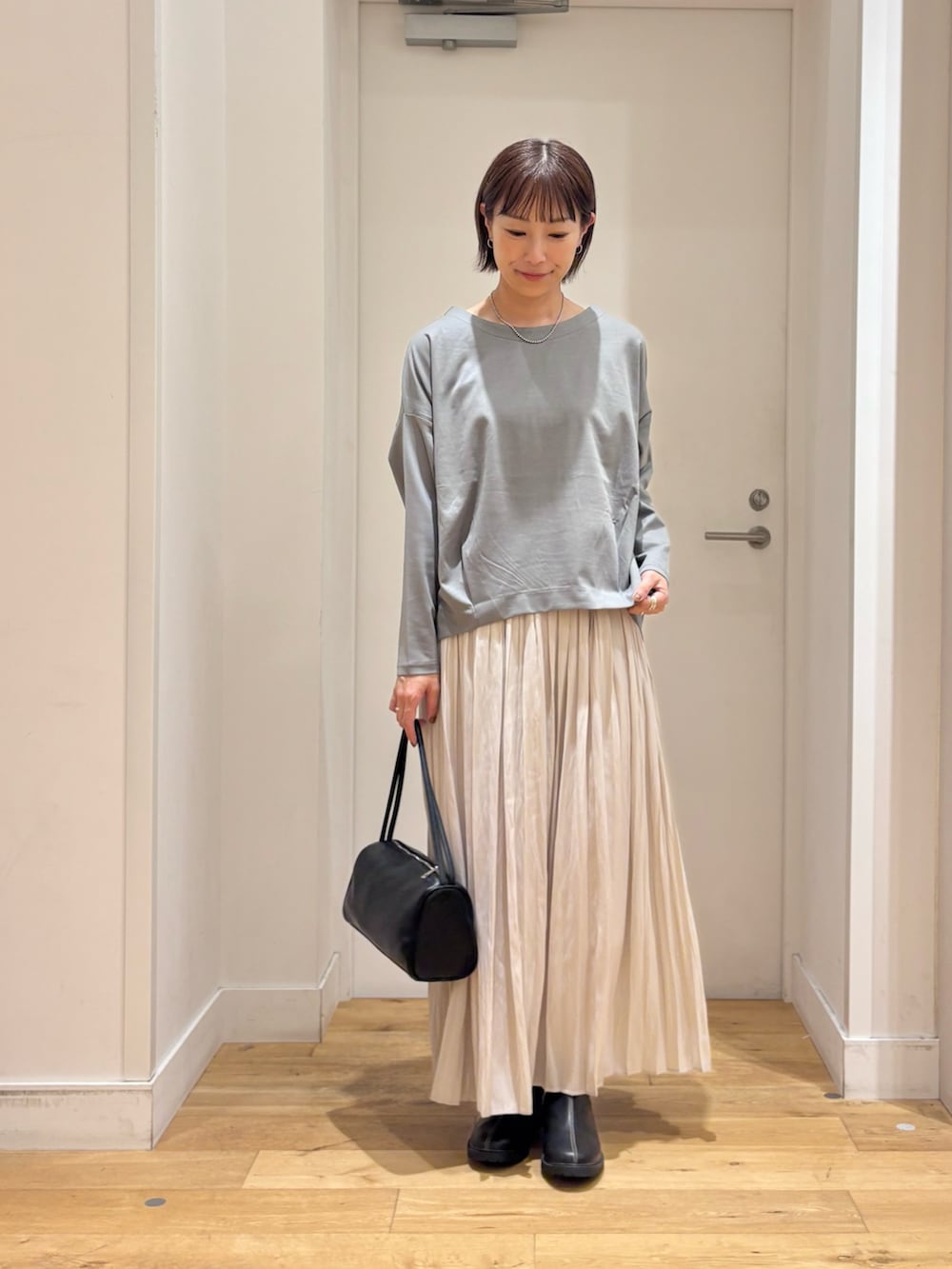 ブルー系のTシャツ/カットソー、ブラック系のハンドバッグ、ブラック系のレインシューズを着用したレディースの秋コーディネートの2枚目の写真