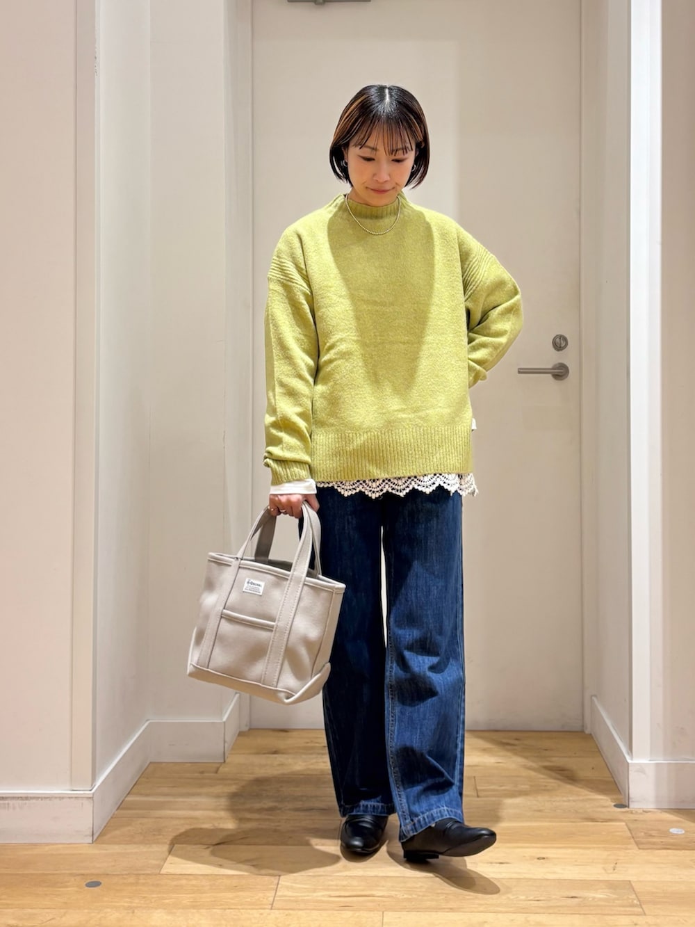 グリーン系のニット/セーター、ホワイト系のTシャツ/カットソー、ベージュ系のトートバッグを着用したレディースの冬コーディネートの2枚目の写真