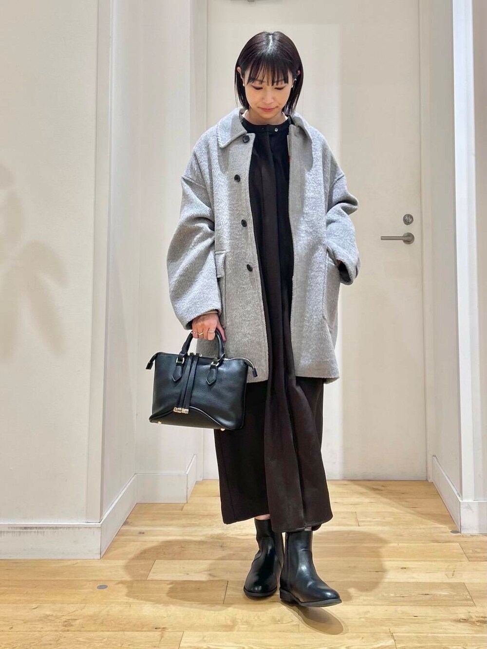 グレー系のその他アウター、ブラック系のボストンバッグ、ブラック系のブーツを着用したレディースの冬コーディネートの3枚目の写真