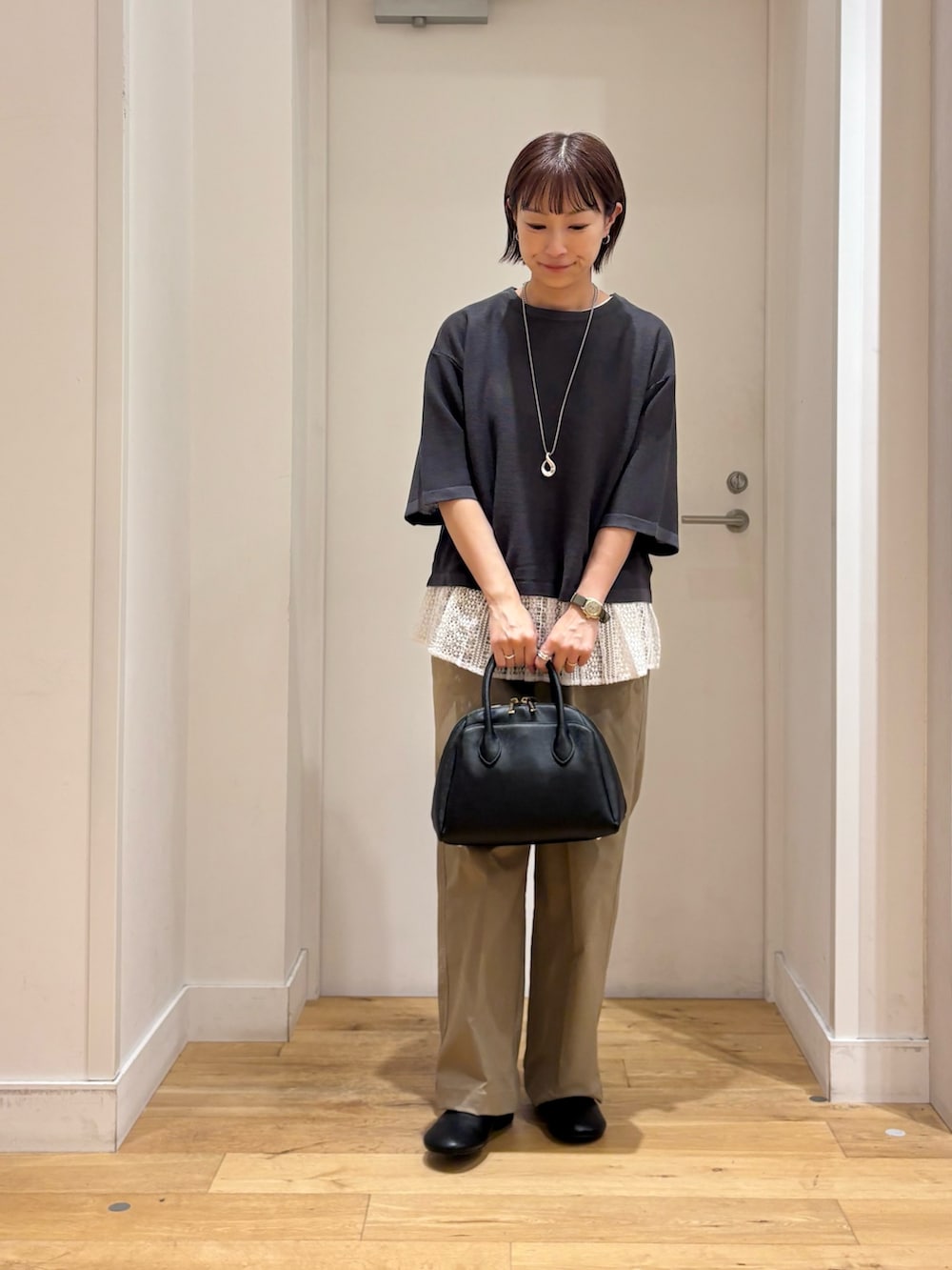 グレー系のニット/セーター、ベージュ系のその他パンツ、ブラック系のハンドバッグを着用したレディースの秋コーディネートの3枚目の写真