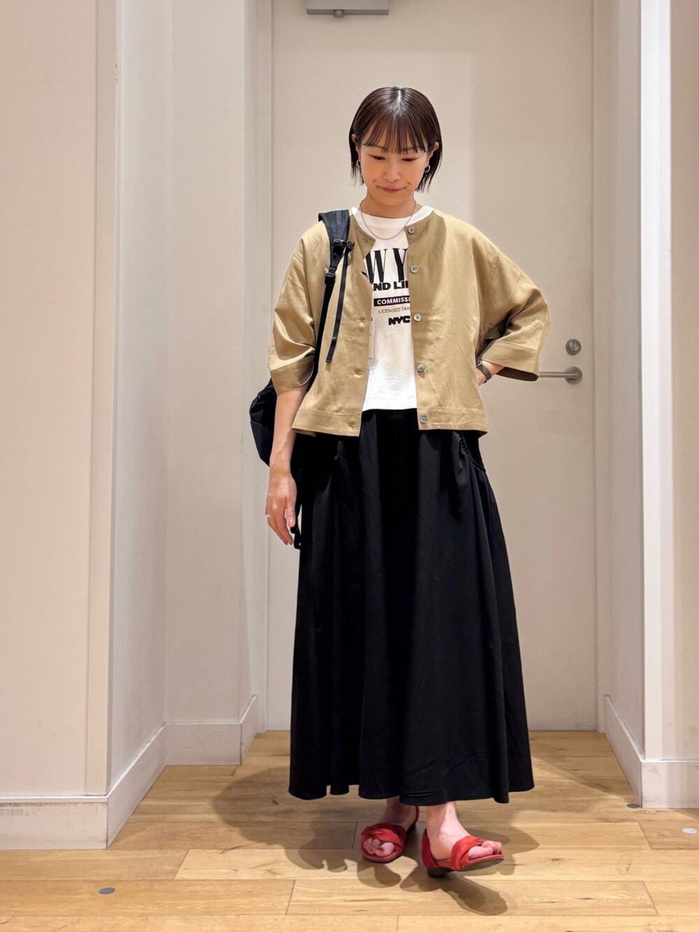 ベージュ系のシャツ/ブラウス、ブラック系のスカート、ホワイト系のTシャツ/カットソーを着用したレディースの春コーディネートの2枚目の写真