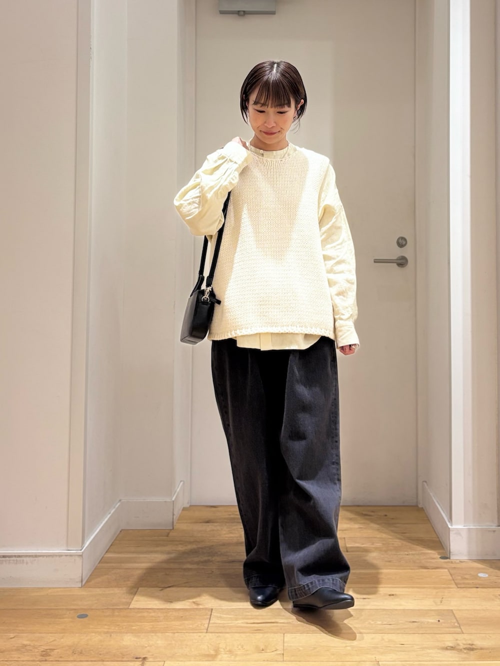 ホワイト系のベスト、ブラック系のデニムパンツ、ブラック系のパンプスを着用したレディースの春コーディネートの2枚目の写真