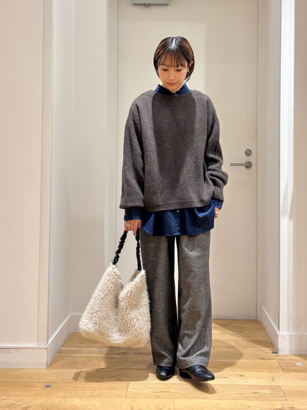 ブラウン系のニット/セーター、グレー系のその他パンツ、ブルー系のシャツ/ブラウスを着用したレディースの秋コーディネートの2枚目の写真