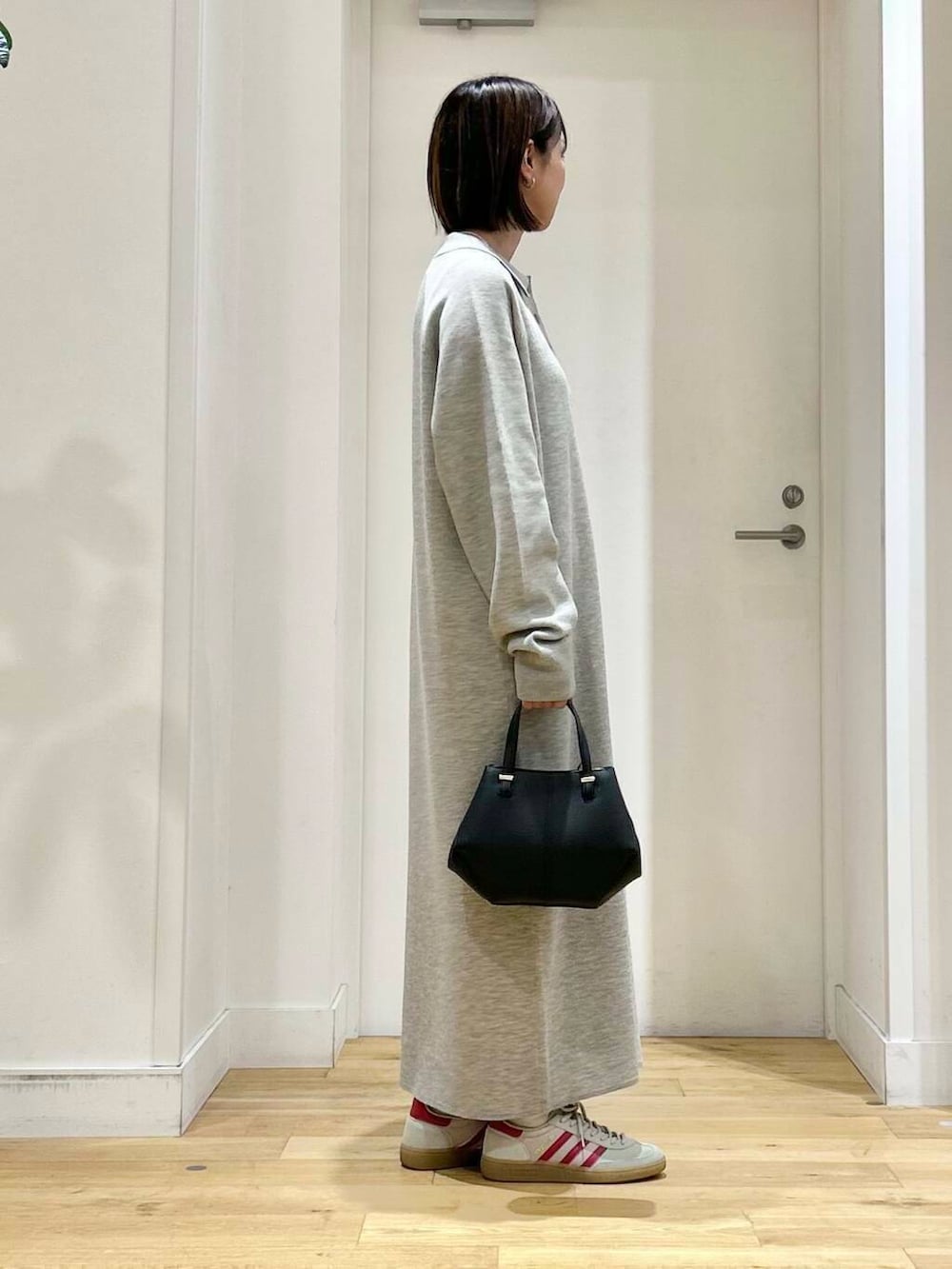 ブラック系のショルダーバッグ、グレー系のワンピース、ホワイト系のスニーカーを着用したレディースの秋コーディネートの4枚目の写真