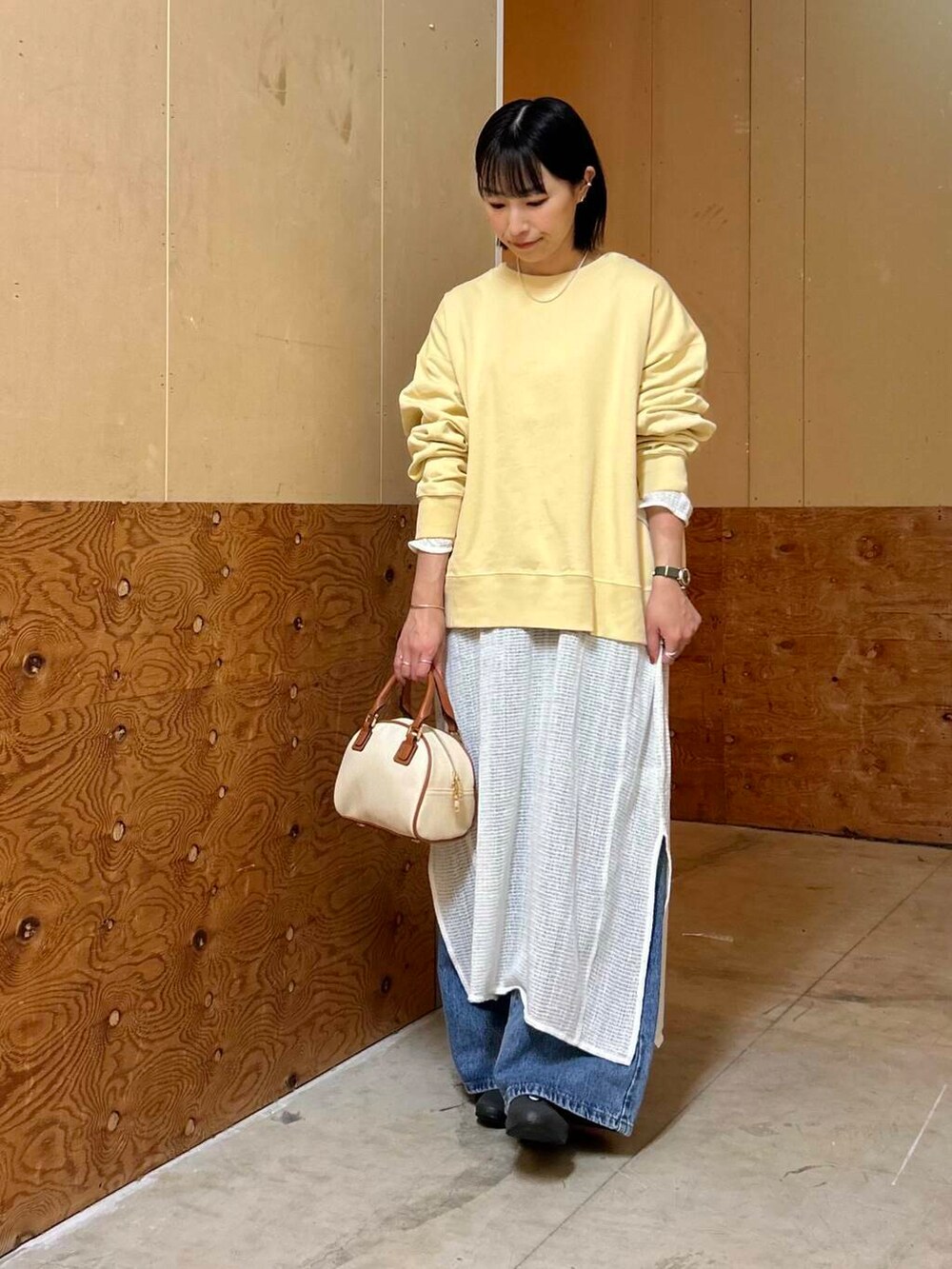 イエロー系のボストンバッグ、イエロー系のスウェット、ホワイト系のワンピースを着用したレディースの春コーディネートの4枚目の写真