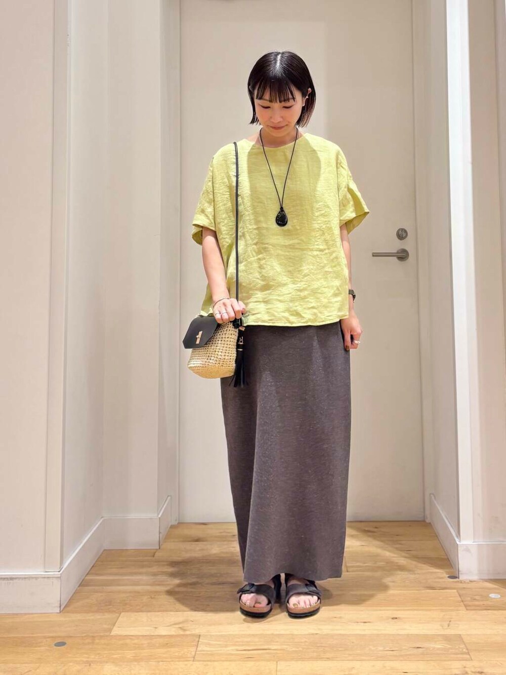 ベージュ系のショルダーバッグ、グレー系のスカート、グレー系のサンダルを着用したレディースの夏コーディネートの3枚目の写真