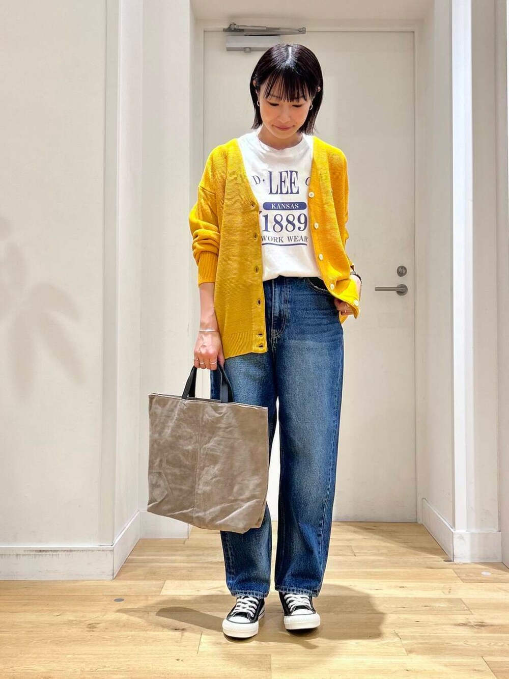 ホワイト系のTシャツ/カットソー、ブラック系のスニーカー、ベージュ系のトートバッグを着用したレディースの秋コーディネートの3枚目の写真