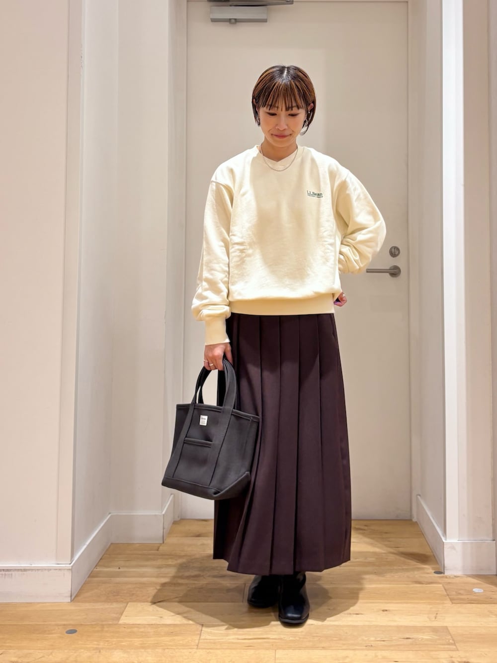 ホワイト系のスウェット、ブラウン系のスカート、グレー系のトートバッグを着用したレディースの秋コーディネートの2枚目の写真