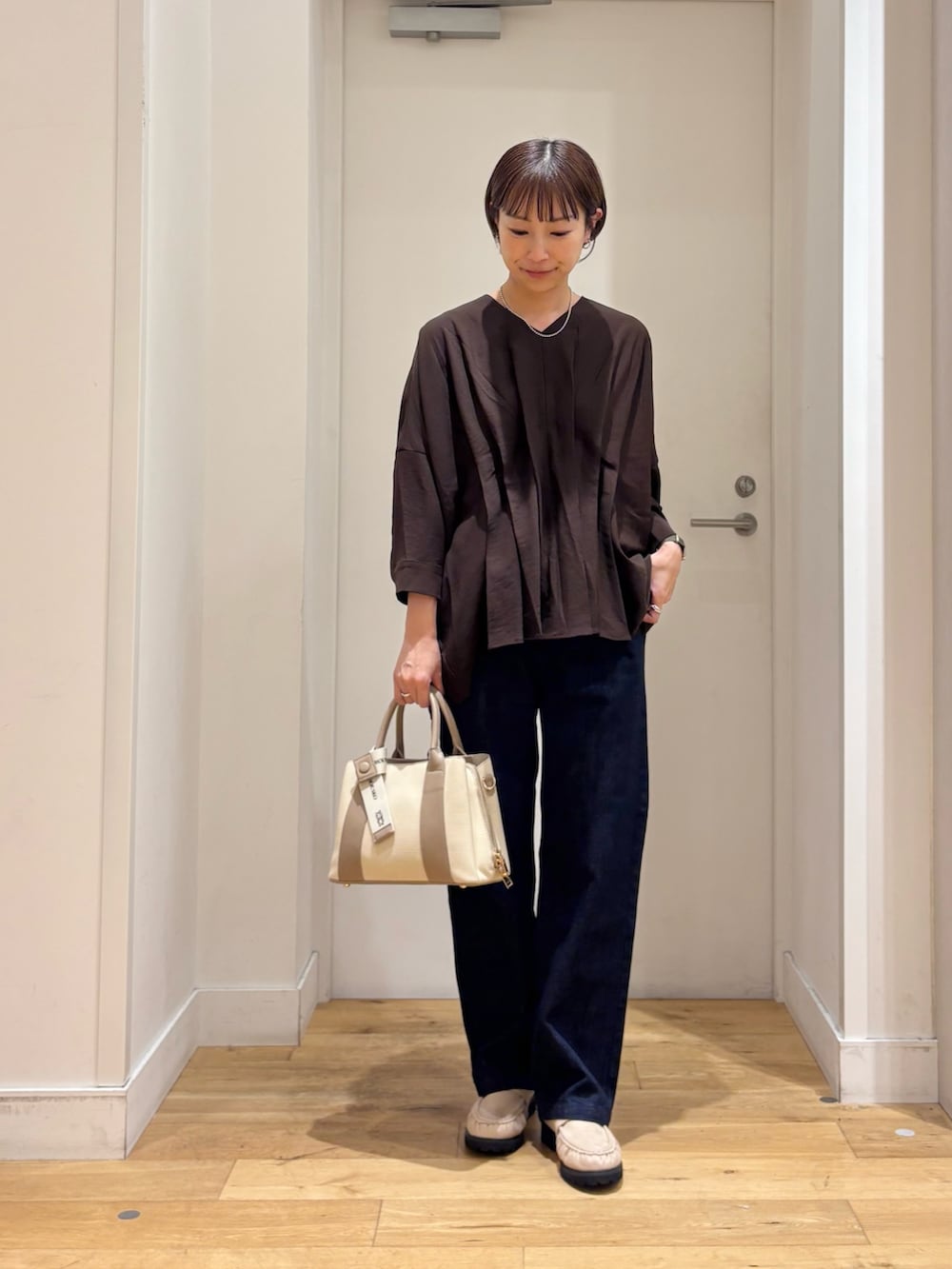 ブラウン系のシャツ/ブラウス、ブルー系のデニムパンツ、ホワイト系のハンドバッグを着用したレディースの秋コーディネートの3枚目の写真