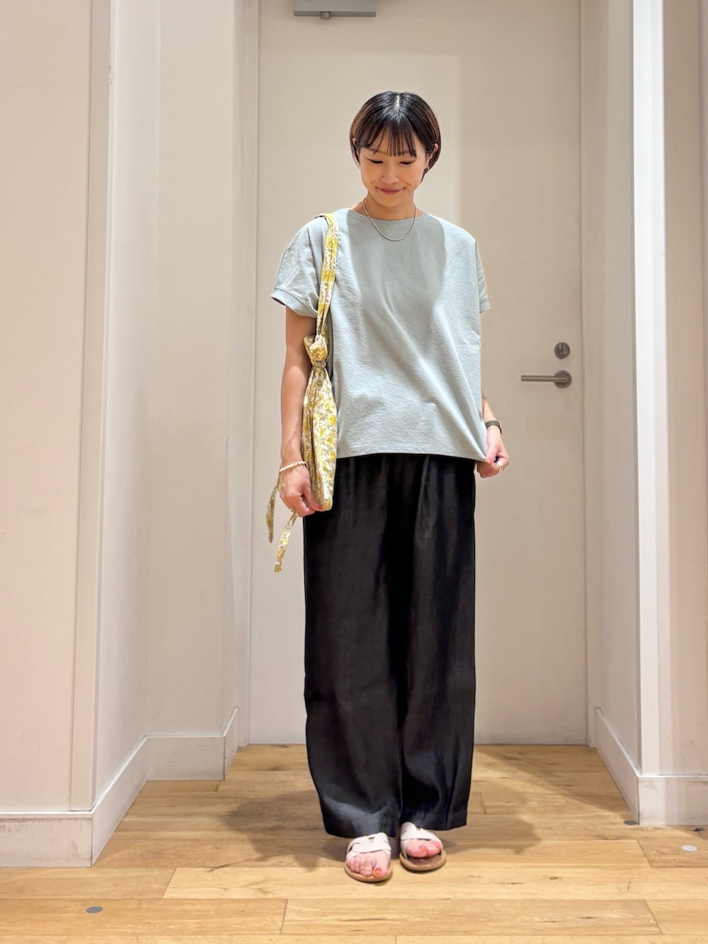 グリーン系のTシャツ/カットソー、ブラック系のデニムパンツ、イエロー系のトートバッグを着用したレディースの夏コーディネートの2枚目の写真