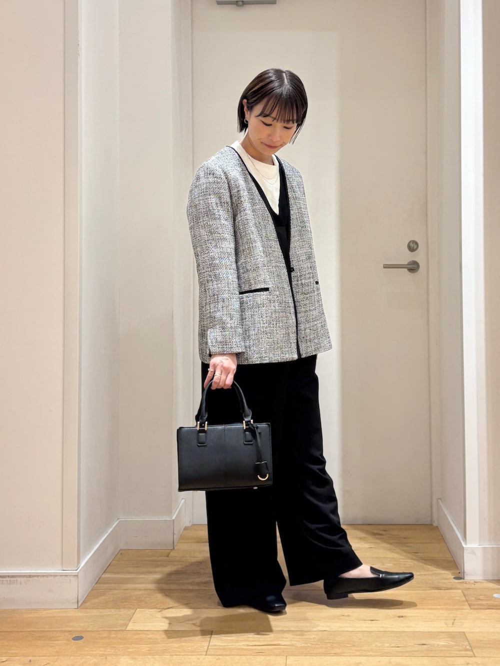 ブラック系のスーツジャケット、ホワイト系のシャツ/ブラウス、ブラック系のハンドバッグを着用したレディースの冬コーディネートの4枚目の写真