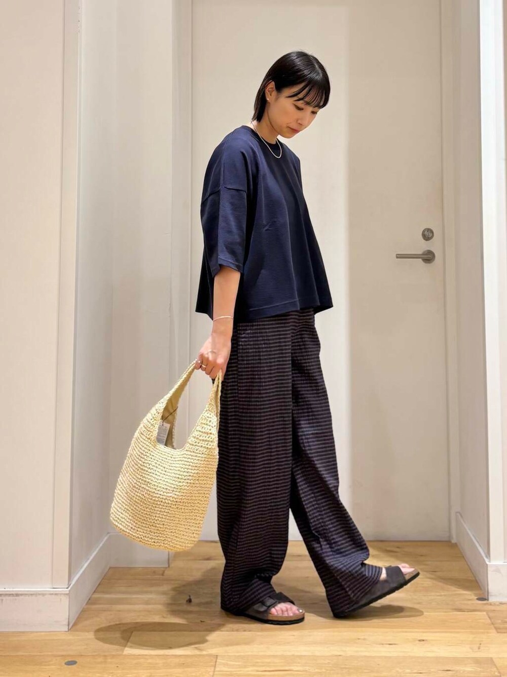 ベージュ系のトートバッグ、グレー系のサンダル、ブルー系のTシャツ/カットソーを着用したレディースの夏コーディネートの4枚目の写真