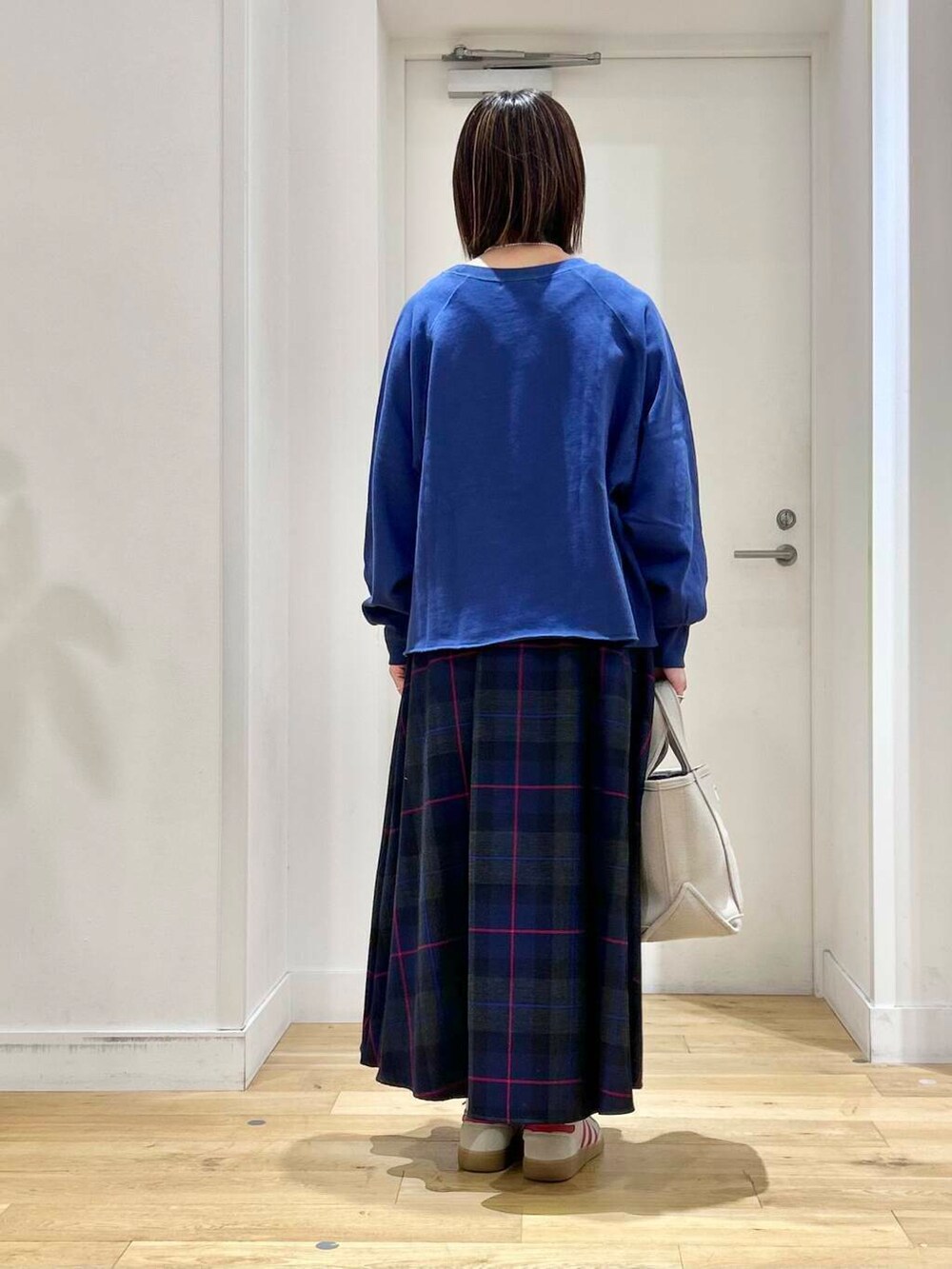 ブルー系のTシャツ/カットソー、ベージュ系のトートバッグ、ホワイト系のスニーカーを着用したレディースの秋コーディネートの5枚目の写真