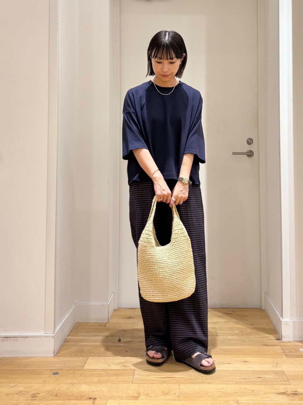 ベージュ系のトートバッグ、グレー系のサンダル、ブルー系のTシャツ/カットソーを着用したレディースの夏コーディネートの2枚目の写真