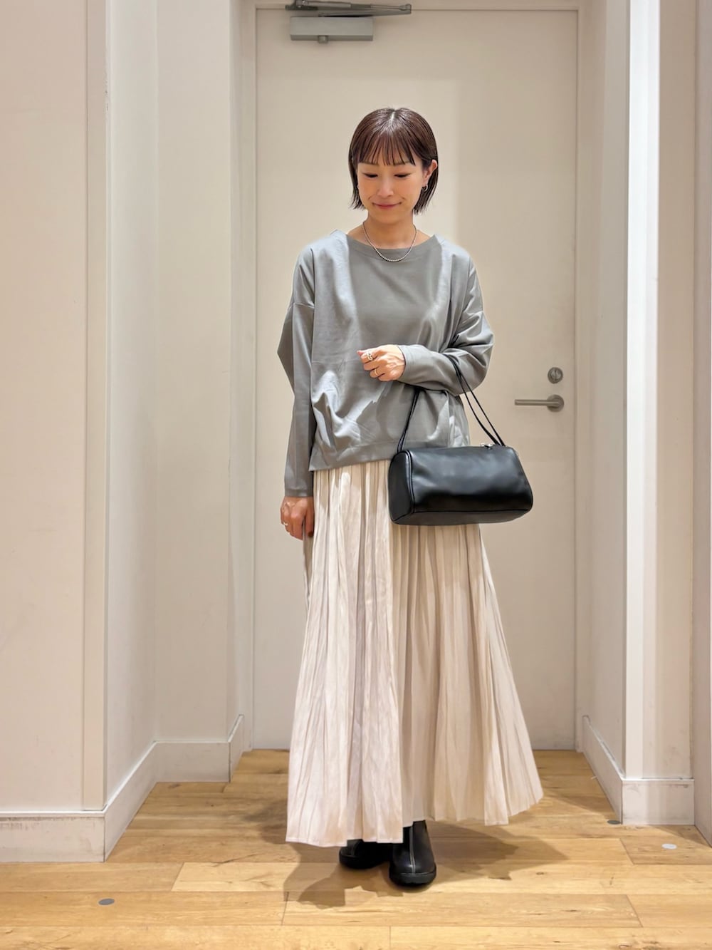 ブルー系のTシャツ/カットソー、ブラック系のハンドバッグ、ブラック系のレインシューズを着用したレディースの秋コーディネートの4枚目の写真