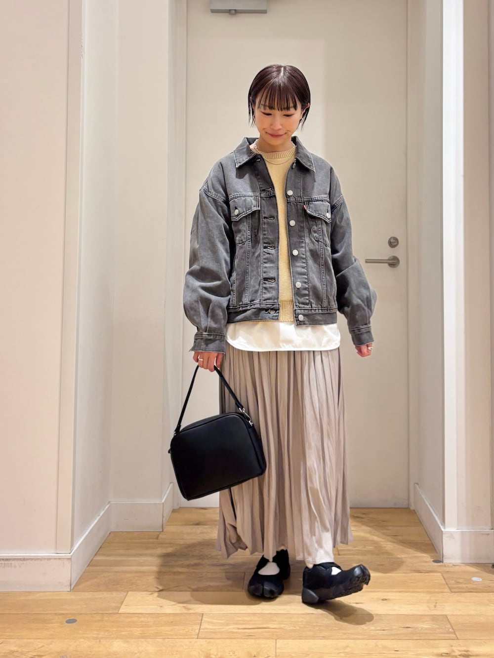 ブラック系のデニムジャケット、ベージュ系のニット/セーター、ホワイト系のTシャツ/カットソーを着用したレディースの春コーディネートの2枚目の写真