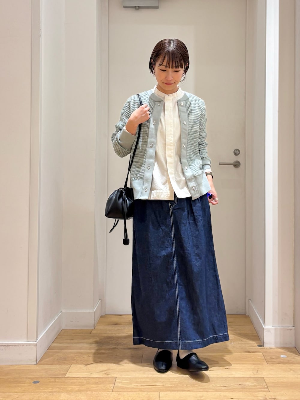 ホワイト系のシャツ/ブラウス、グリーン系のカーディガン/ボレロ、ブルー系のスカートを着用したレディースの春コーディネートの2枚目の写真