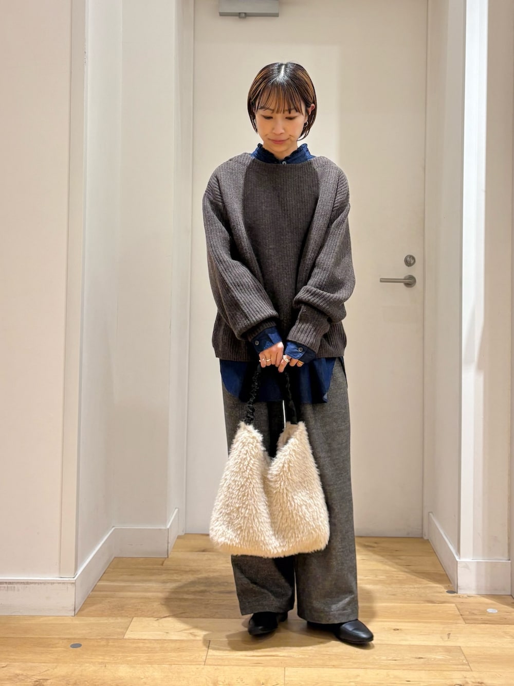 ブラウン系のニット/セーター、グレー系のその他パンツ、ブルー系のシャツ/ブラウスを着用したレディースの秋コーディネートの3枚目の写真