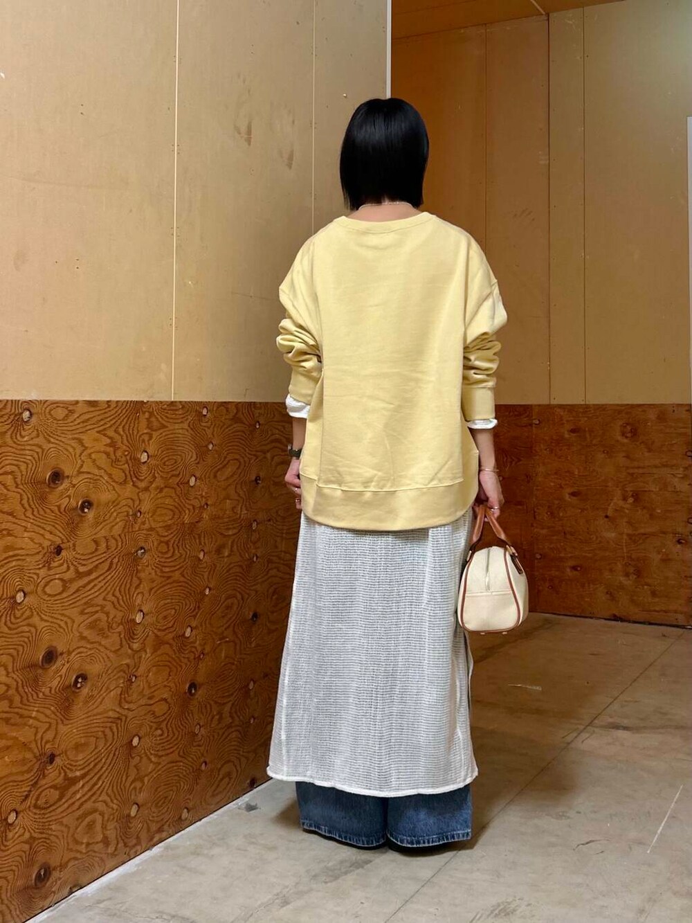 イエロー系のボストンバッグ、イエロー系のスウェット、ホワイト系のワンピースを着用したレディースの春コーディネートの6枚目の写真