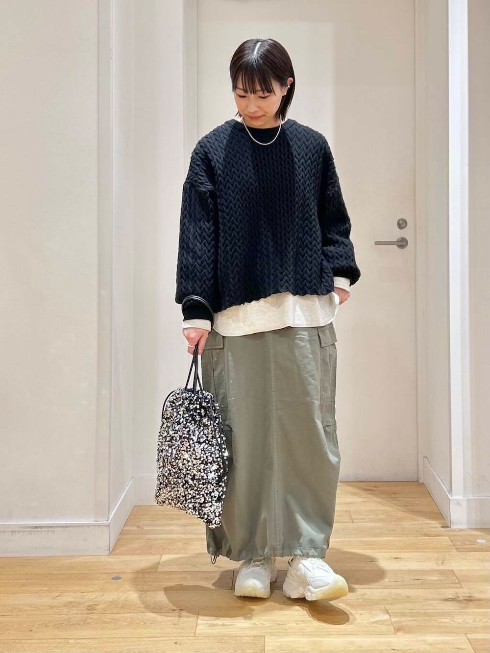 グリーン系のスカート、ホワイト系のスニーカー、シルバー系のトートバッグを着用したレディースの冬コーディネートの2枚目の写真