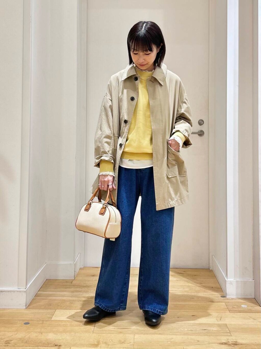 ホワイト系のシャツ/ブラウス、イエロー系のニット/セーター、ブルー系のデニムパンツを着用したレディースの冬コーディネートの3枚目の写真