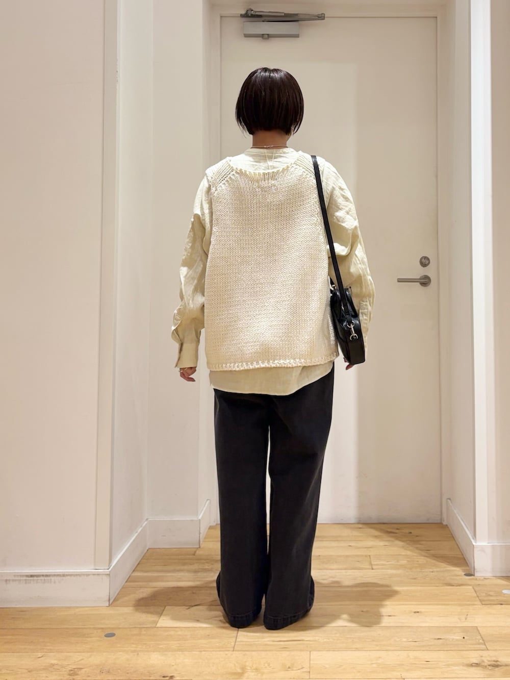 ホワイト系のベスト、ブラック系のデニムパンツ、ブラック系のパンプスを着用したレディースの春コーディネートの5枚目の写真