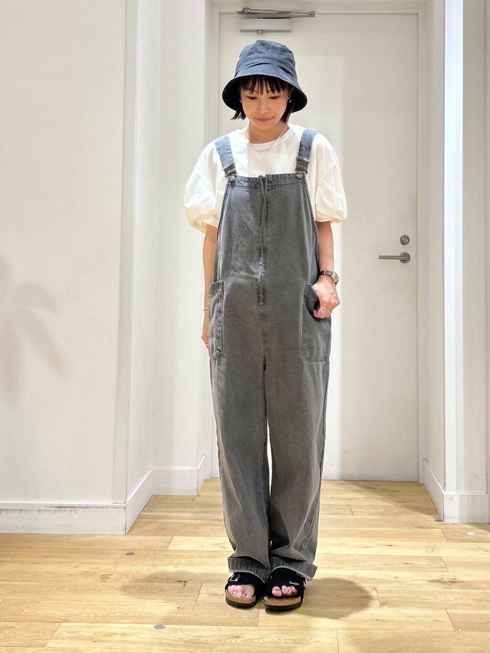 ブラック系のサンダル、グレー系のサロペット/オーバーオール、ホワイト系のTシャツ/カットソーを着用したレディースの夏コーディネートの3枚目の写真