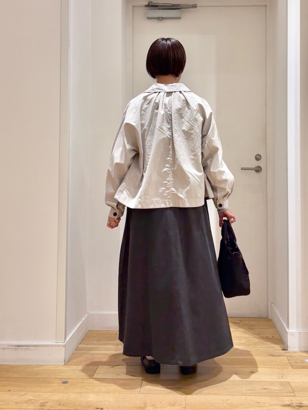 レッド系のスウェット、ベージュ系のテーラードジャケット、グリーン系のワンピースを着用したレディースの春コーディネートの6枚目の写真