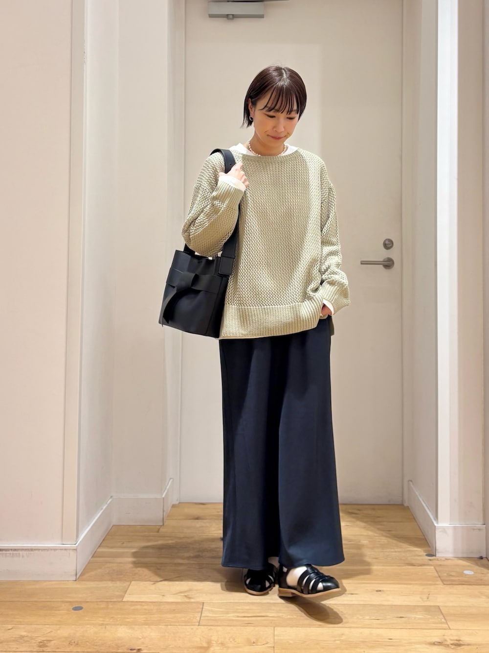 グリーン系のニット/セーター、ホワイト系のTシャツ/カットソー、ブルー系のスカートを着用したレディースの春コーディネートの2枚目の写真