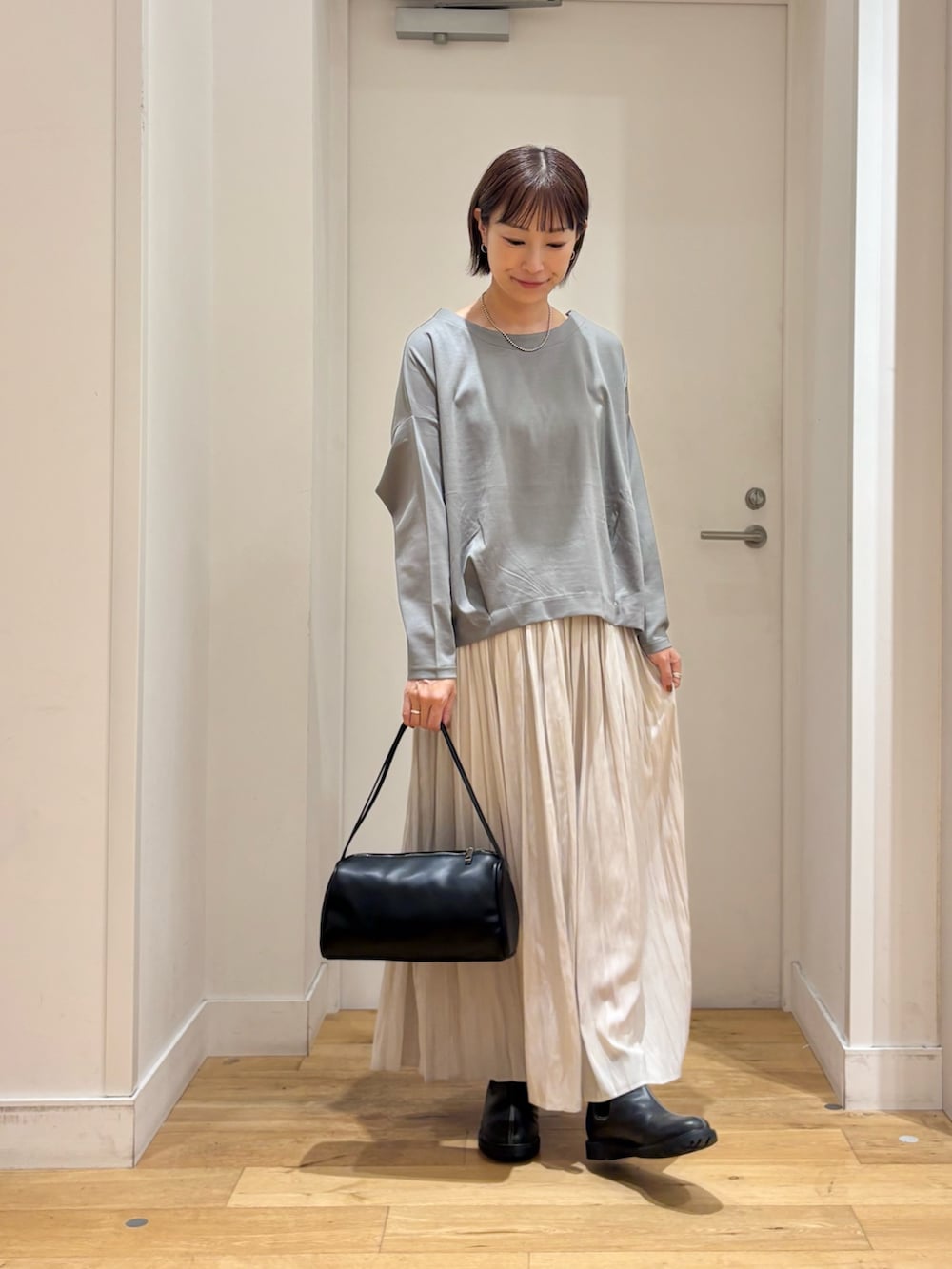 ブルー系のTシャツ/カットソー、ブラック系のハンドバッグ、ブラック系のレインシューズを着用したレディースの秋コーディネートの5枚目の写真