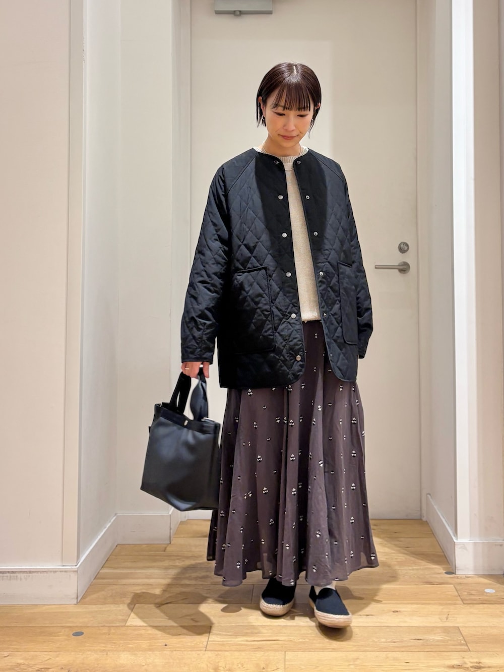 ブラック系のハンドバッグ、グレー系のニット/セーター、グレー系のスカートを着用したレディースの春コーディネートの4枚目の写真