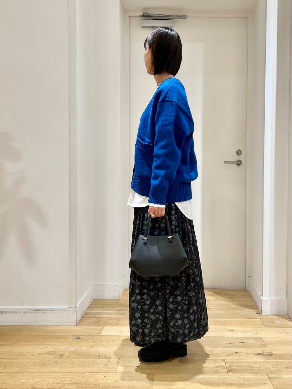 ブラック系のショルダーバッグ、ブラック系のブーツ、ブルー系のカーディガン/ボレロを着用したレディースの冬コーディネートの4枚目の写真