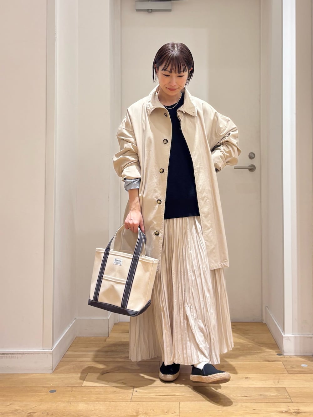 ホワイト系のTシャツ/カットソー、ベージュ系のステンカラーコート、ブルー系のベストを着用したレディースの春コーディネートの3枚目の写真