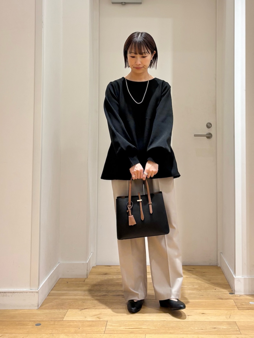 ブラック系のニット/セーター、ベージュ系のその他パンツ、ブラック系のパンプスを着用したレディースの冬コーディネートの2枚目の写真