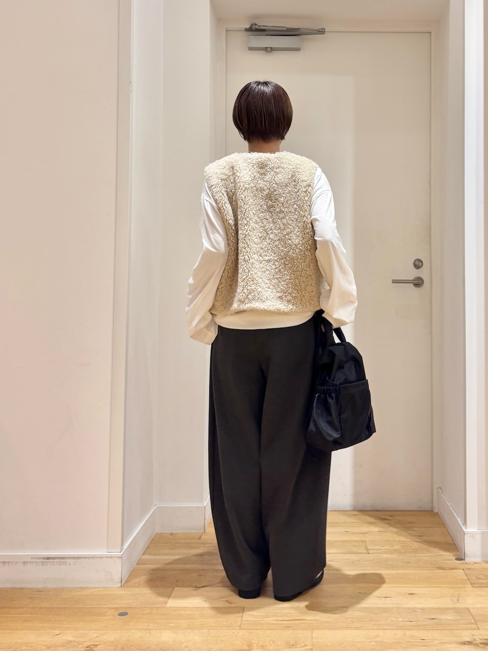 ベージュ系のダウンベスト、グレー系のその他パンツ、ホワイト系のTシャツ/カットソーを着用したレディースの秋コーディネートの6枚目の写真